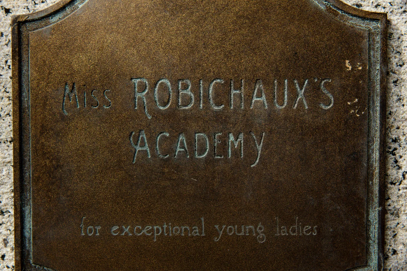 The weathered Miss Robichaux's Academy plaque stands outside the Coven school in a Disney and FX publicity photograph.