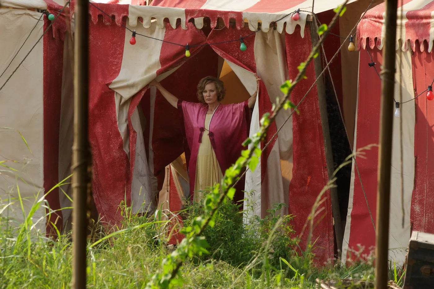 Jessica Lange as Elsa Mars stands at the opening of a red-and-white striped circus tent in a Freak Show publicity photograph.