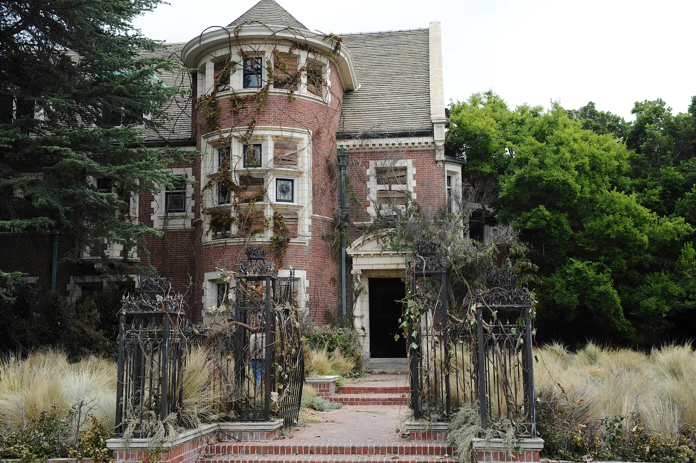 The Murder House exterior stands behind an iron gate in an official publicity photograph for American Horror Story Season 1.
