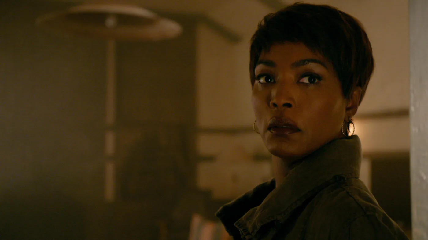 Adina Porter as Lee Harris looks back over her shoulder in a dim room in an official Roanoke publicity still.