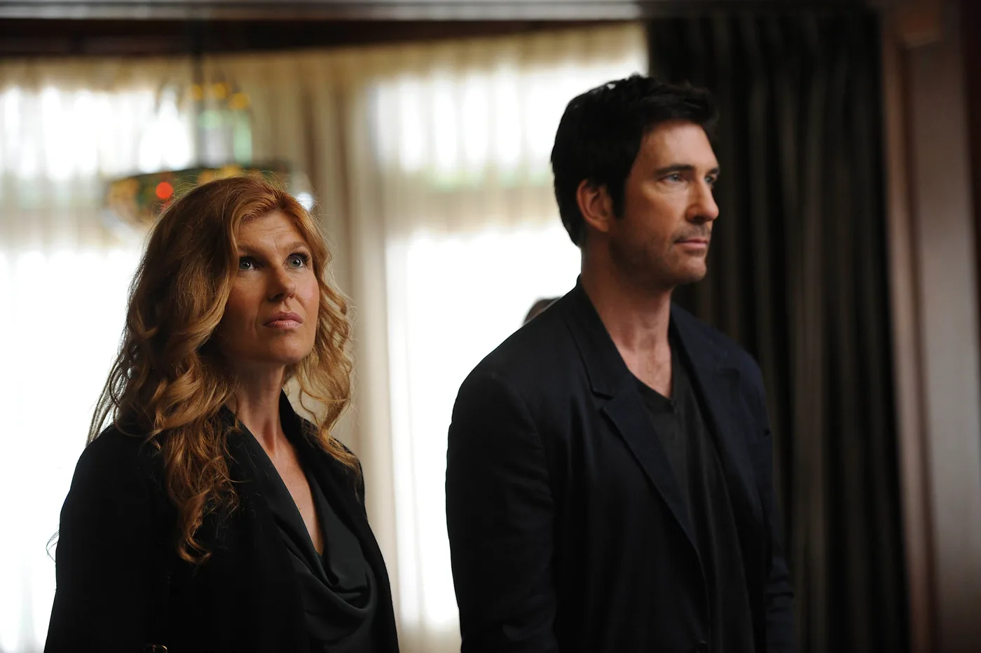 Connie Britton as Vivien Harmon stands beside Dylan McDermott as Ben Harmon inside the Murder House.