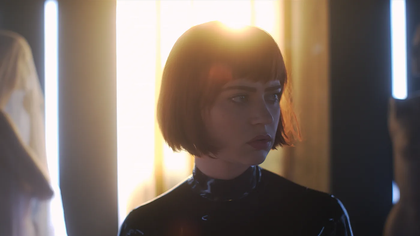 A short-haired woman in dark clothing stands under bright interior light in an official American Horror Stories publicity still.