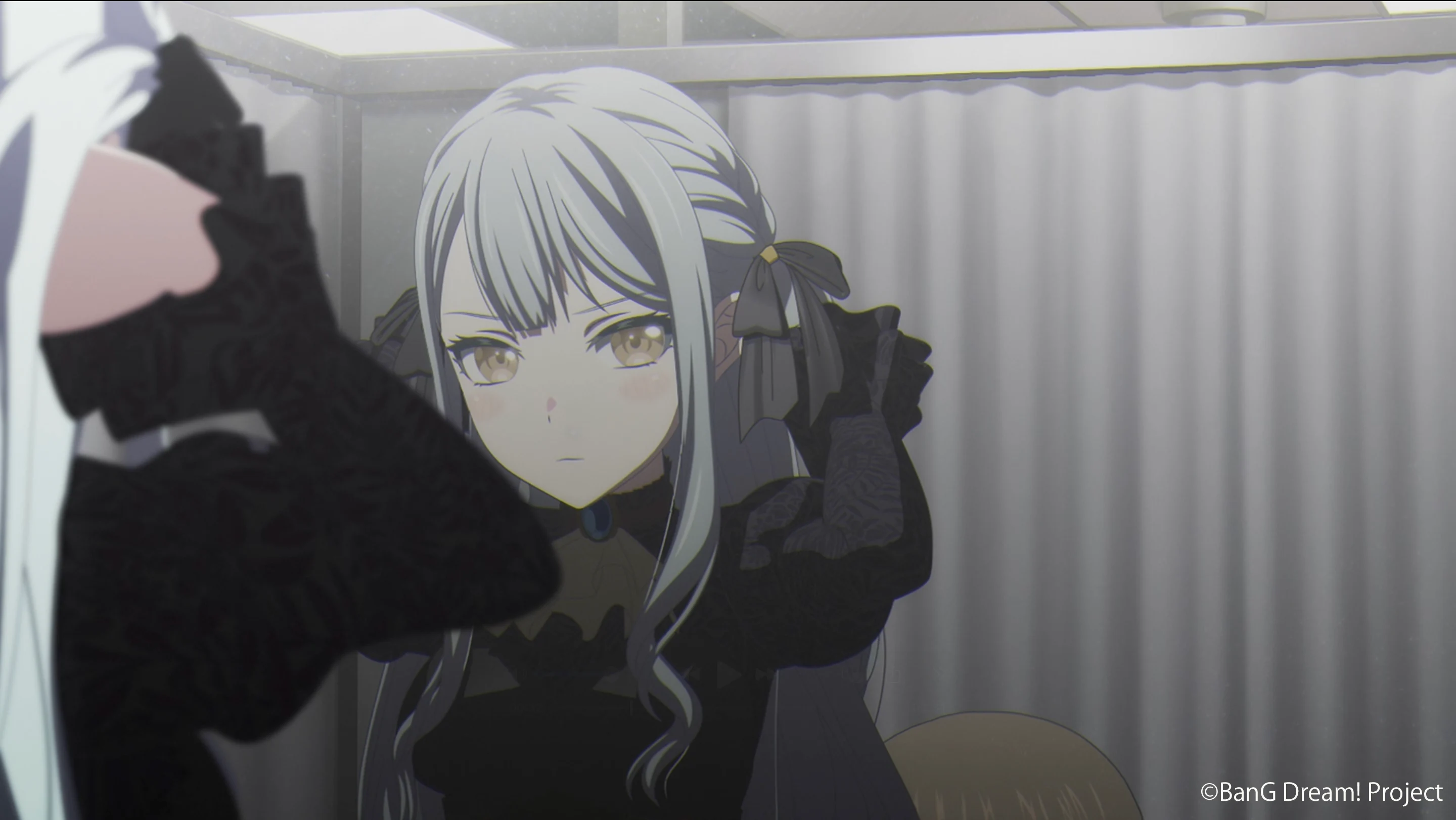 An Ave Mujica member in a black ruffled stage costume appears in a mirror in an official teaser still.