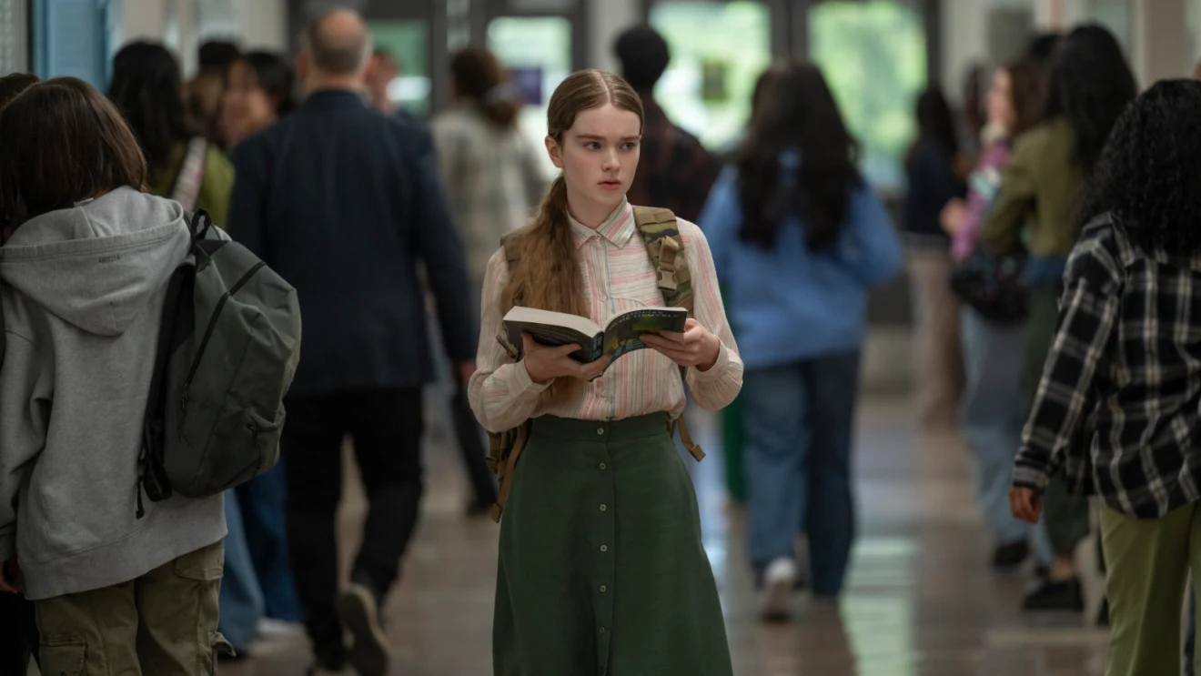 Summer H. Howell as Carrie White looks around a busy high school hallway while holding a book in Carrie (2026).