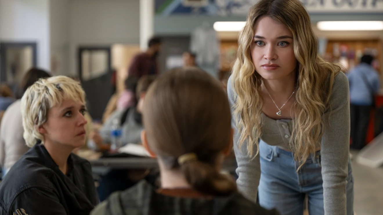 Alison Thornton as Chris Hargensen leaning toward Carrie in a tense high school cafeteria scene.