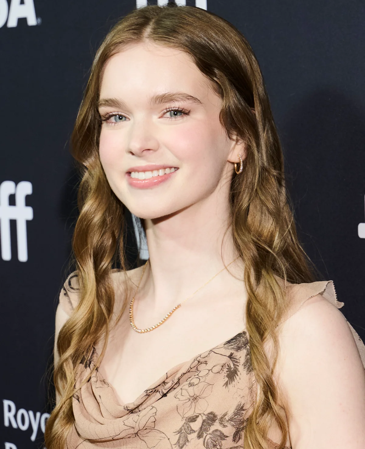 Summer H. Howell smiling at the Carrie premiere, wearing a beige dress against a Toronto International Film Festival backdrop.