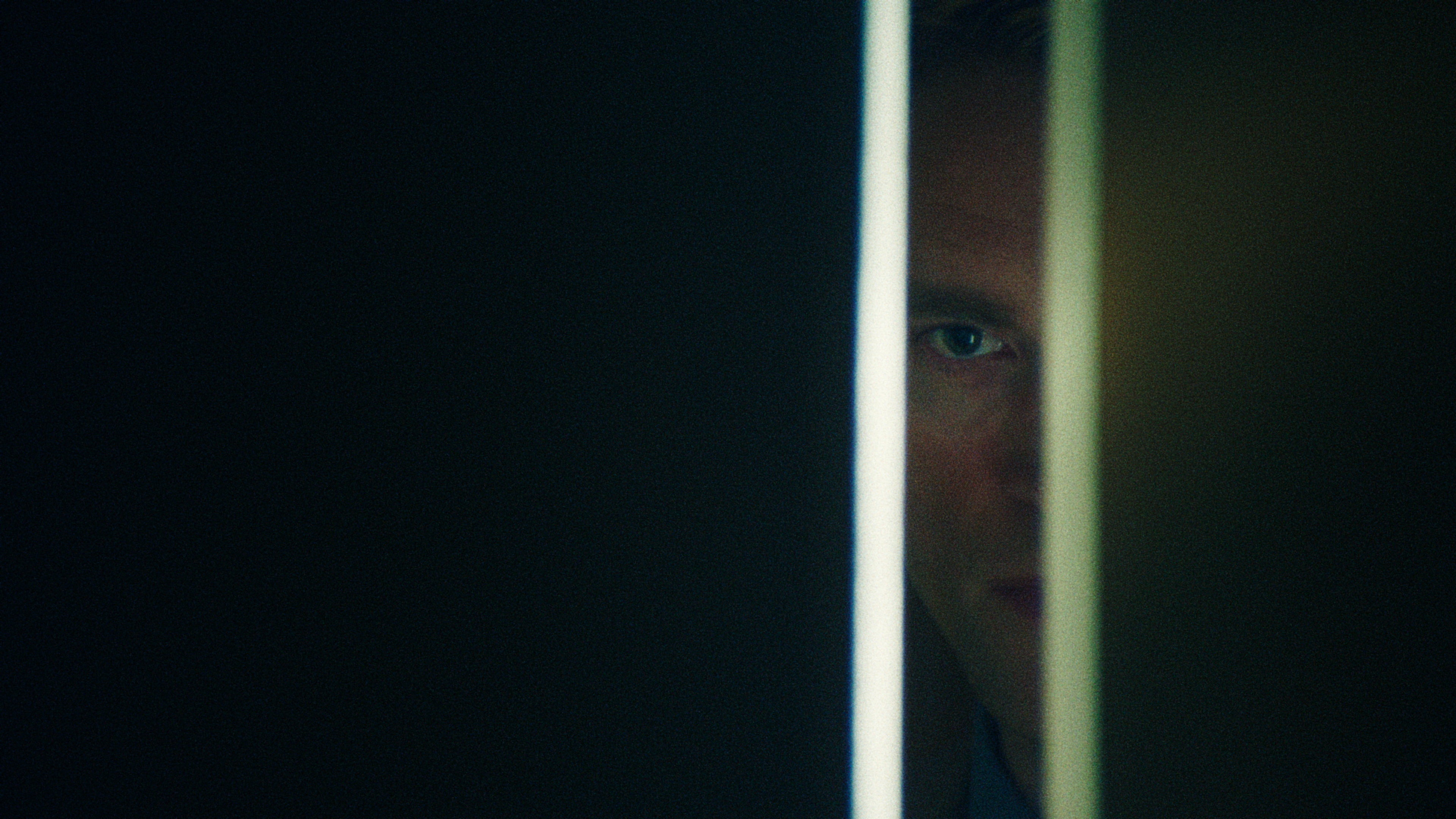 Robert Pattinson as Chris Hansen in A24's Primetime, seen through a narrow doorway