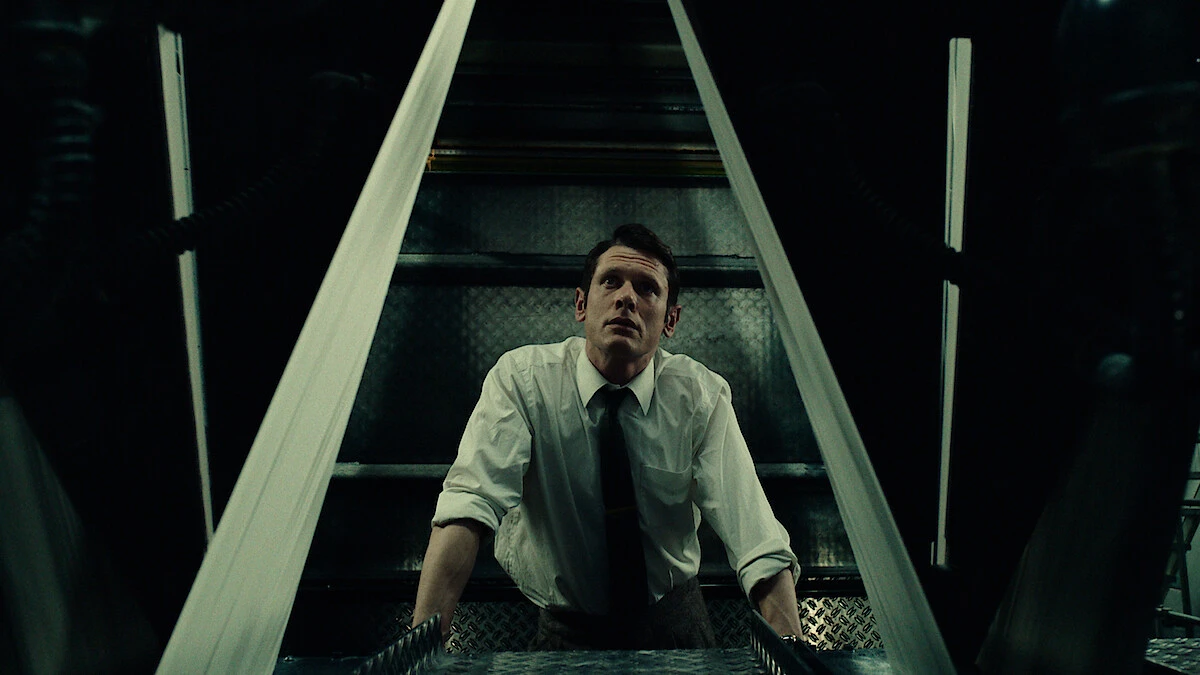 Jack O'Connell as Larry Lamb standing in a dimly lit industrial newsroom setting in Danny Boyle's Ink.