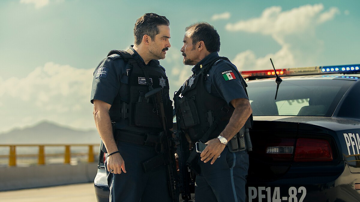 Officers Arturo Carmona (Alfonso Herrera) and Héctor Rosales (Noé Hernández) in a tense face-off beside a marked Mexican federal police car in Facing El Chapo.