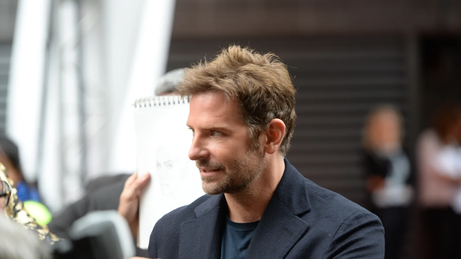 Bradley Cooper wearing a dark jacket at a public event in 2018.