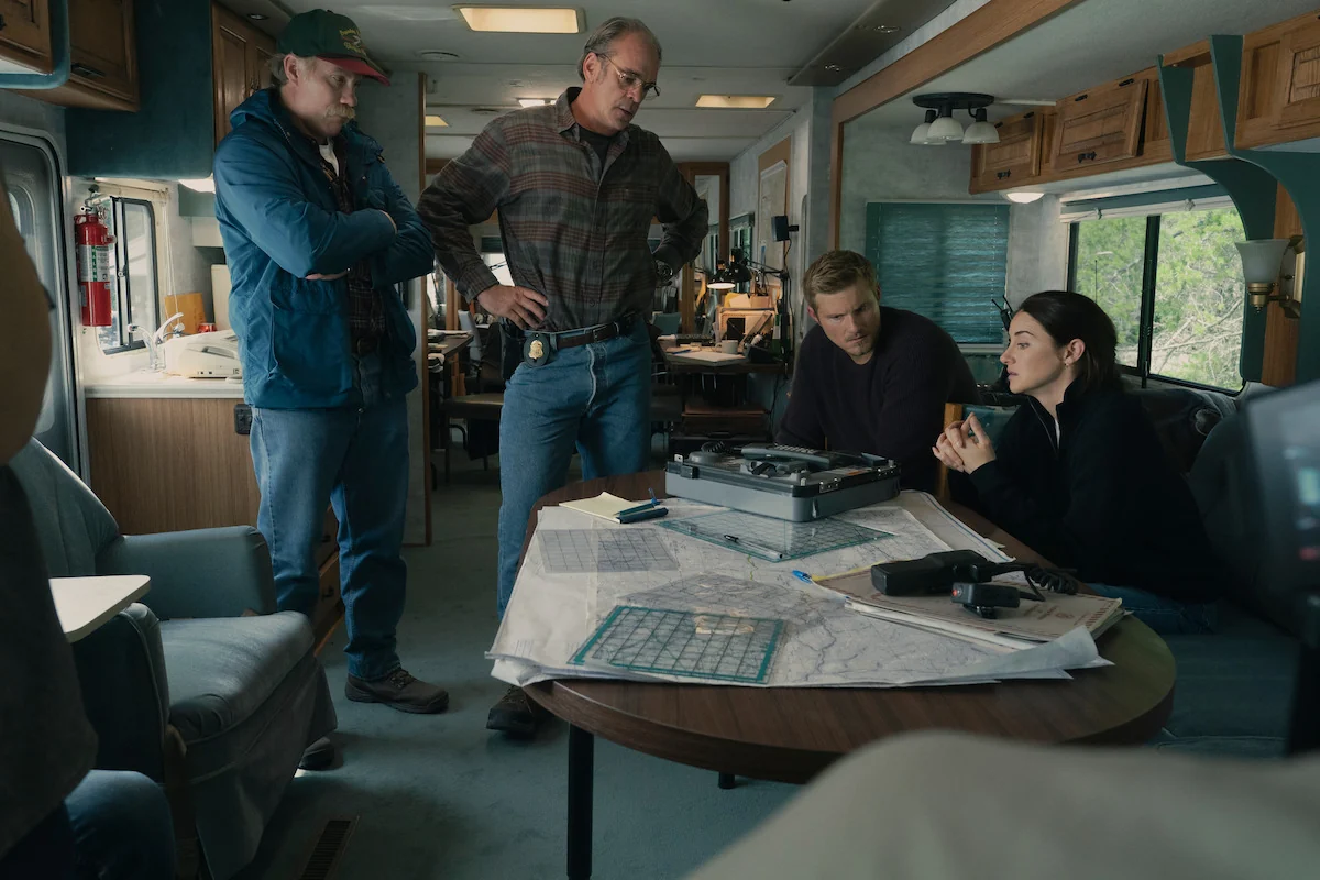 Four fictional FBI agents, including Shailene Woodley as Joanne Miller, gather around maps inside an RV in Netflix’s UNABOMBER.