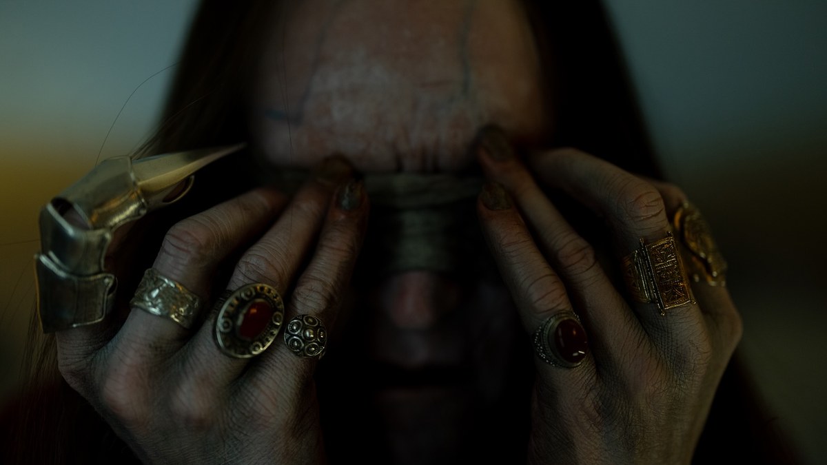 Cyrus Lam (Sam Spruell) in Insidious: Out of the Further, hands raised in a ritual gesture.