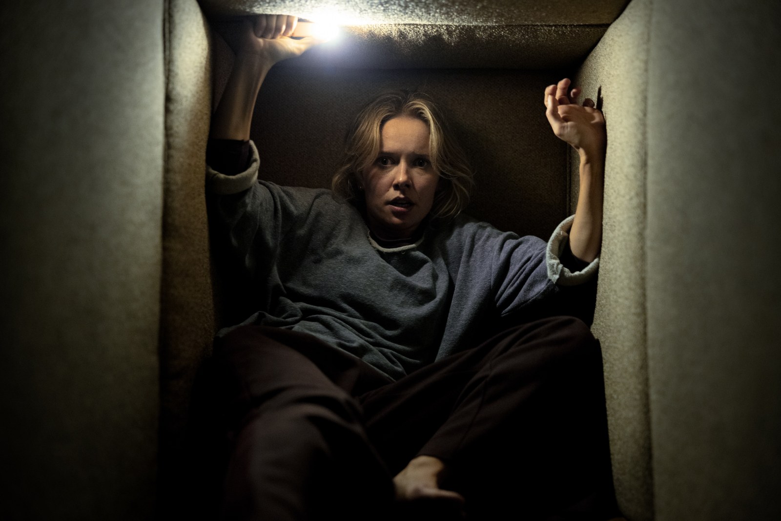 Gemma (Amelia Eve) trapped in a narrow crawlspace, reaching upward in Insidious: Out of the Further.