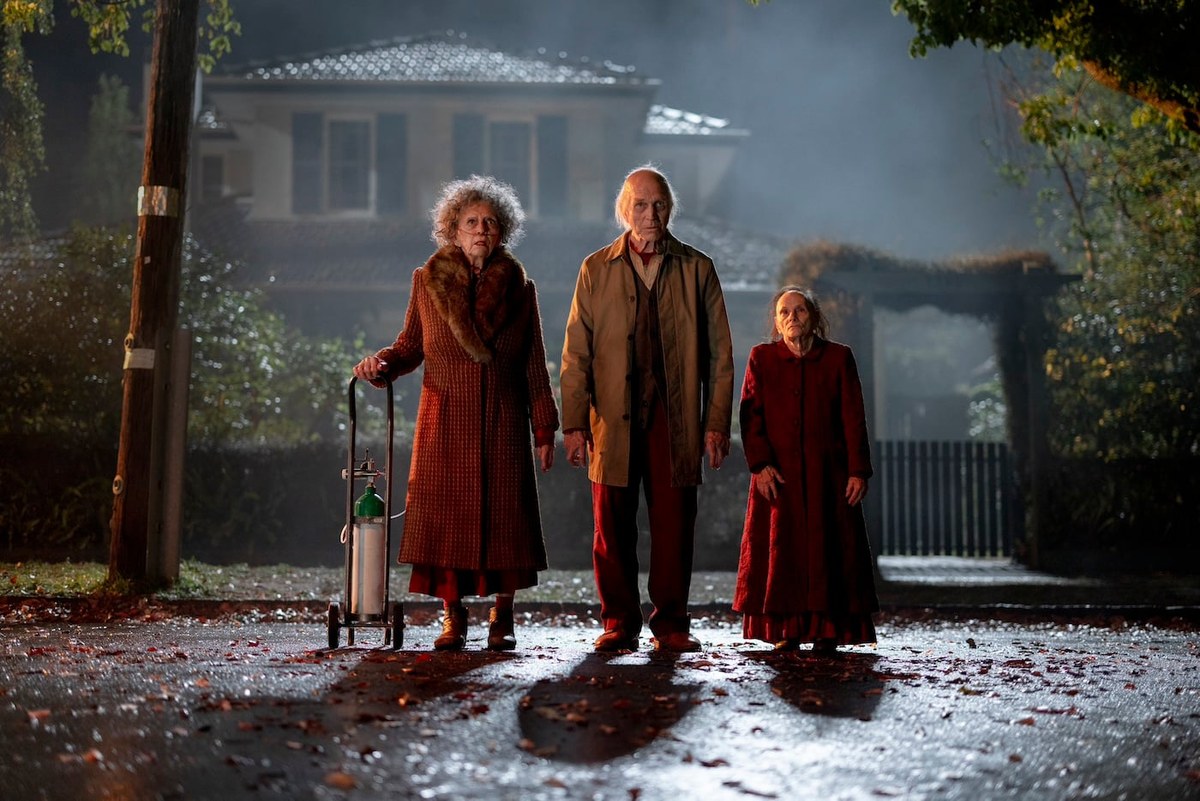 Cyrus's three elderly acolytes standing outside a fog-shrouded house in Insidious: Out of the Further.