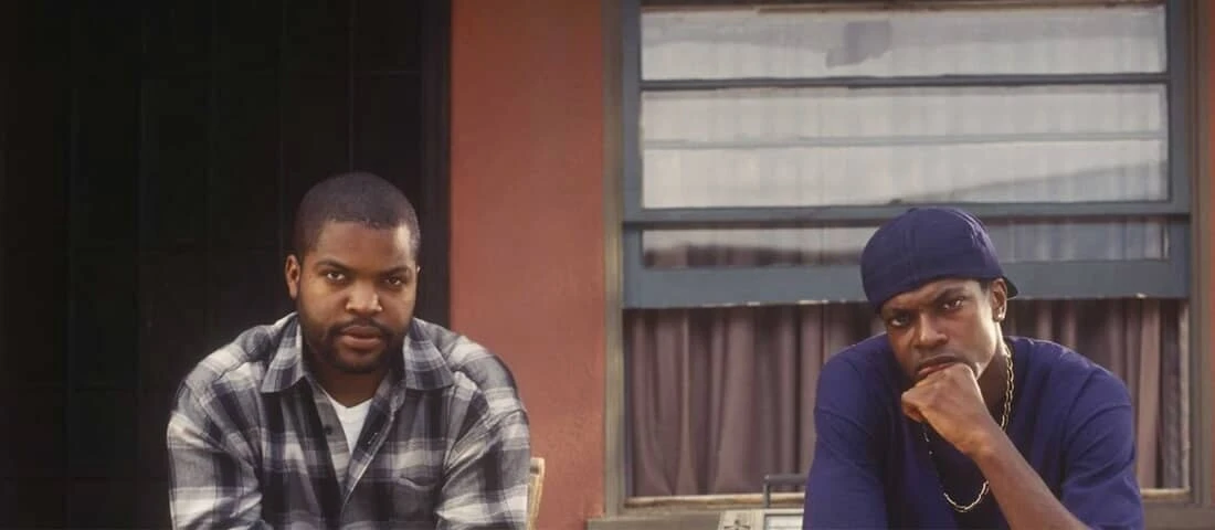Archival Friday (1995) production image showing Ice Cube as Craig Jones and Chris Tucker as Smokey seated outside a house.