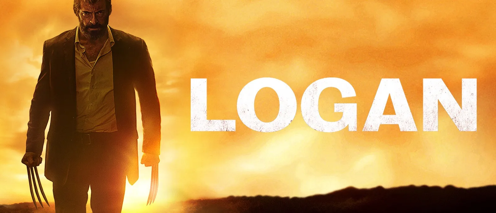 Hugh Jackman as Logan standing in an abandoned industrial area in a still from Logan.