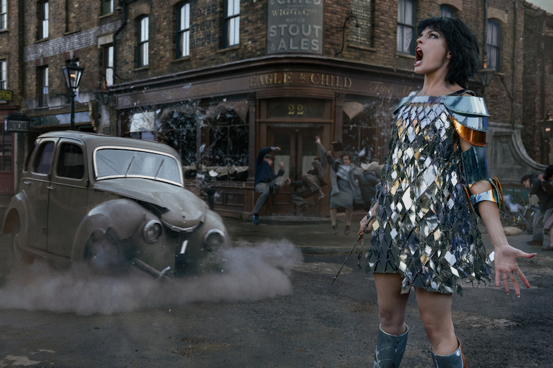 Emma Mackey as Jadis wearing a silver outfit on a city street in Netflix's Narnia first look.
