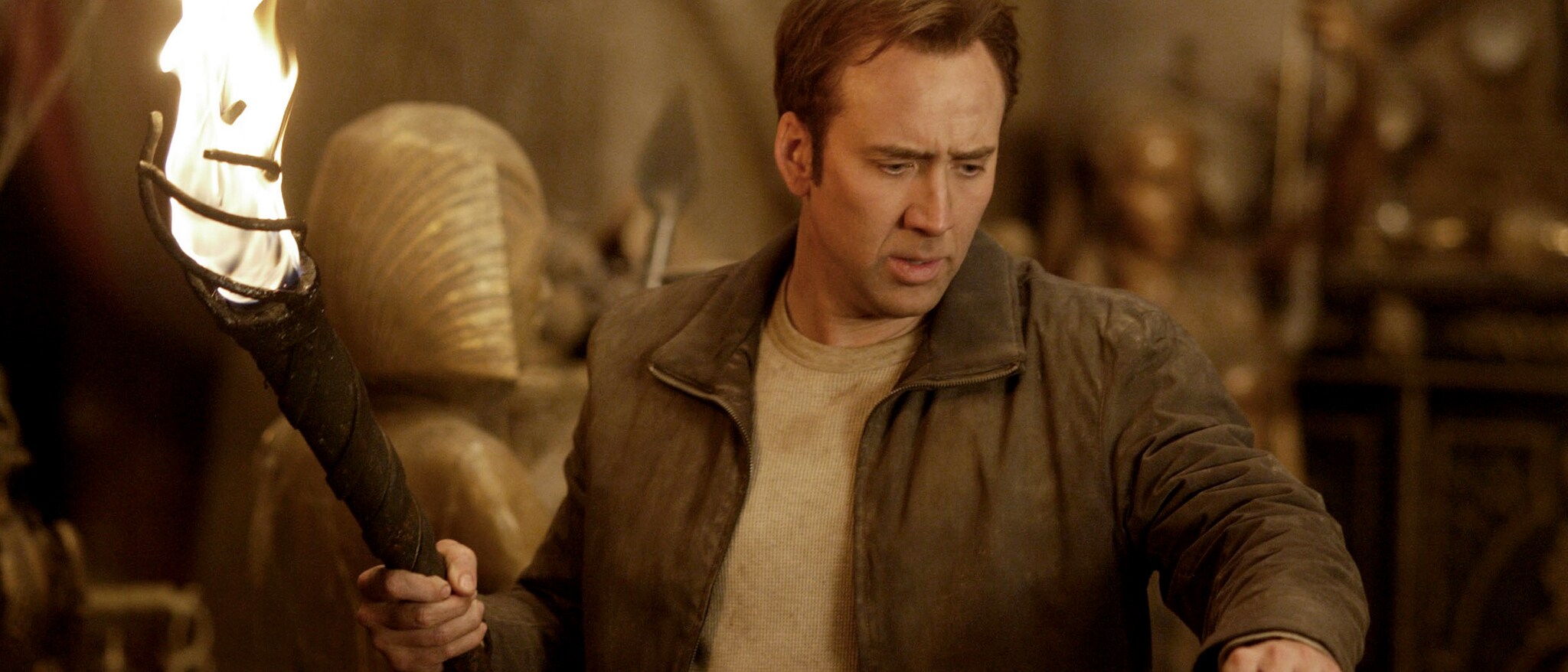 Nicolas Cage as Ben Gates holding a flaming torch in Disney's National Treasure.
