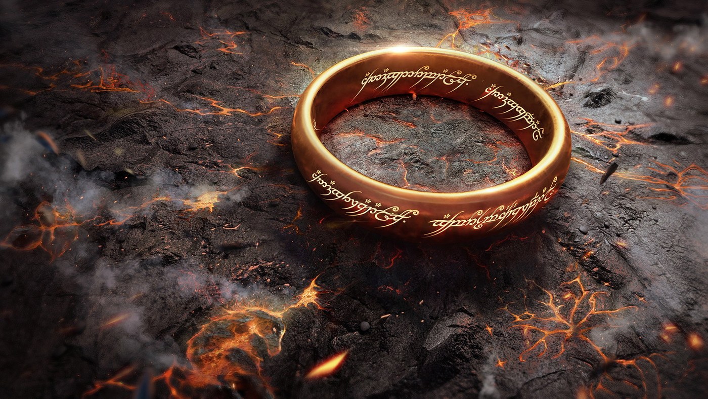 The One Ring, with its Elvish inscription visible, resting on volcanic rock.