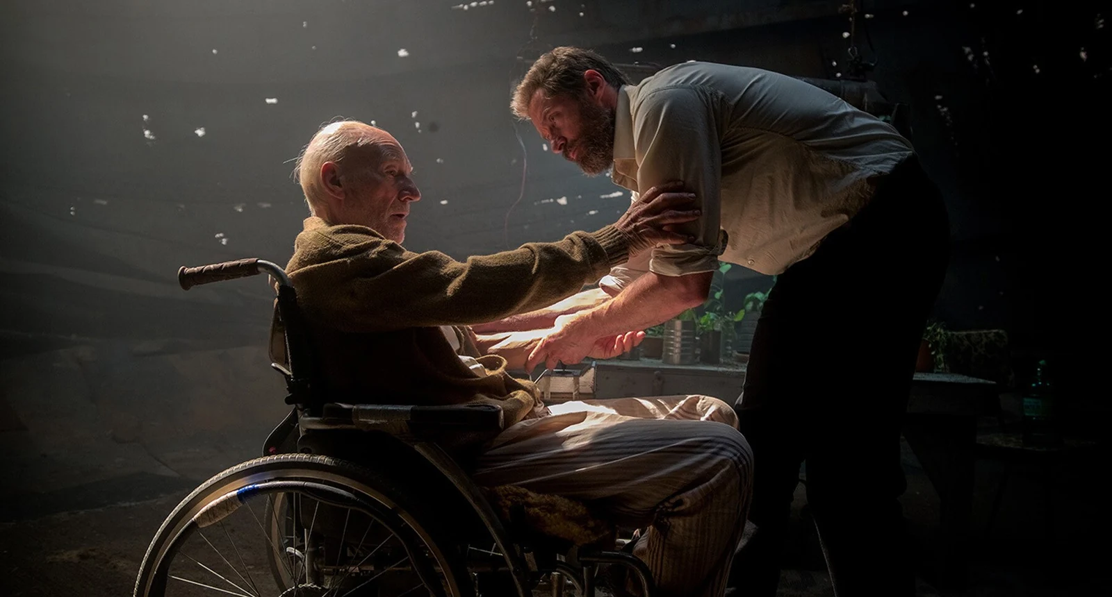 Patrick Stewart as Charles Xavier reaches toward Hugh Jackman as Logan in a scene from Logan.