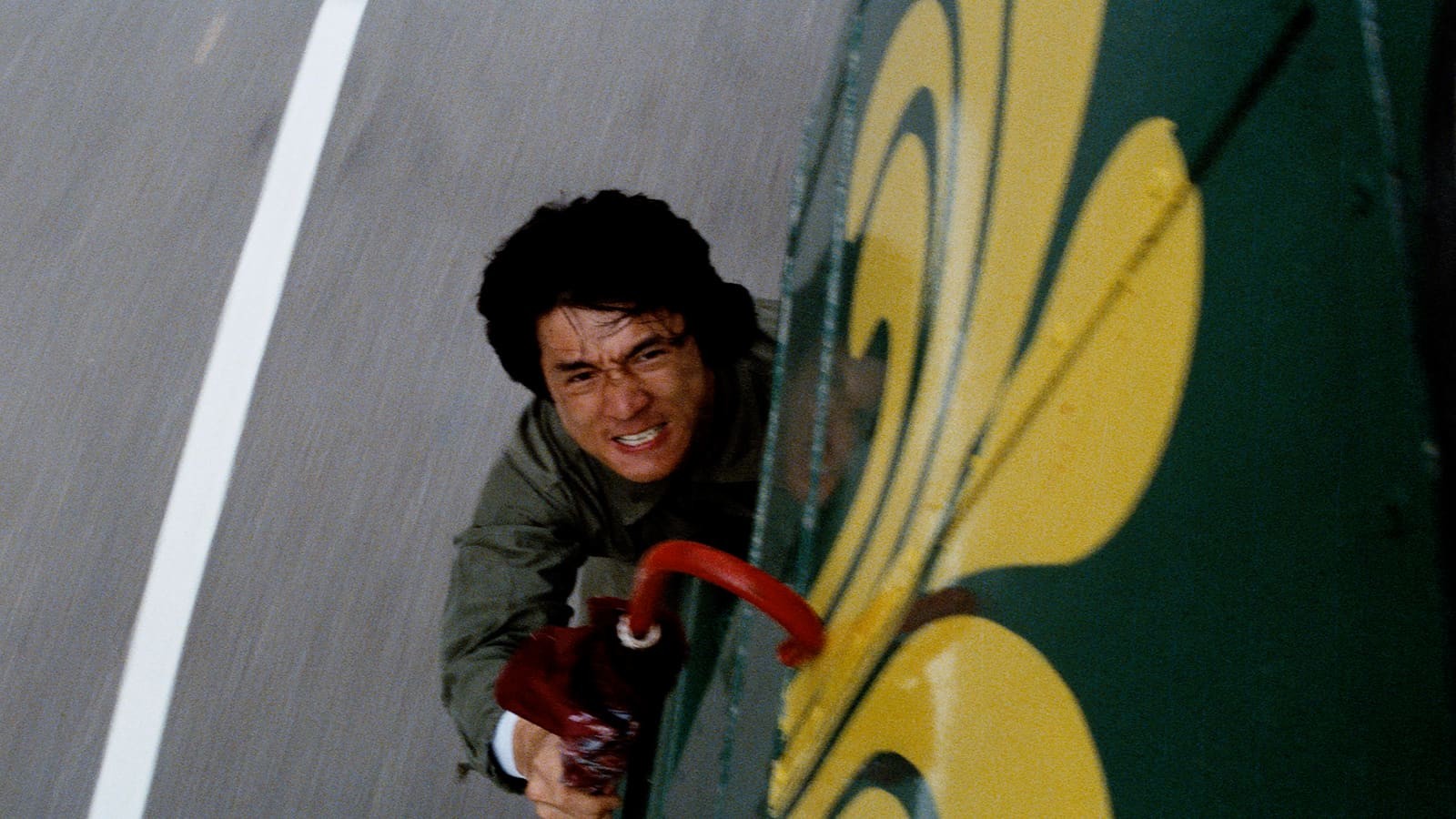 Jackie Chan clinging to a moving bus in a Janus Films still from Police Story.