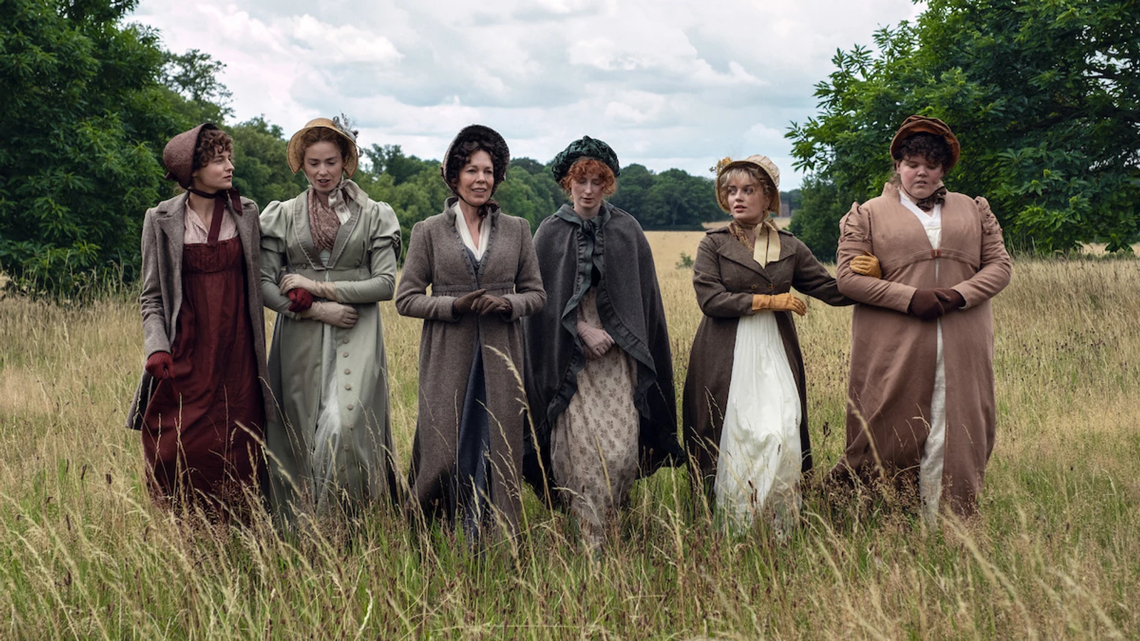 Official Netflix first-look image of the Bennet family walking together through a field in period costume in Pride and Prejudice.