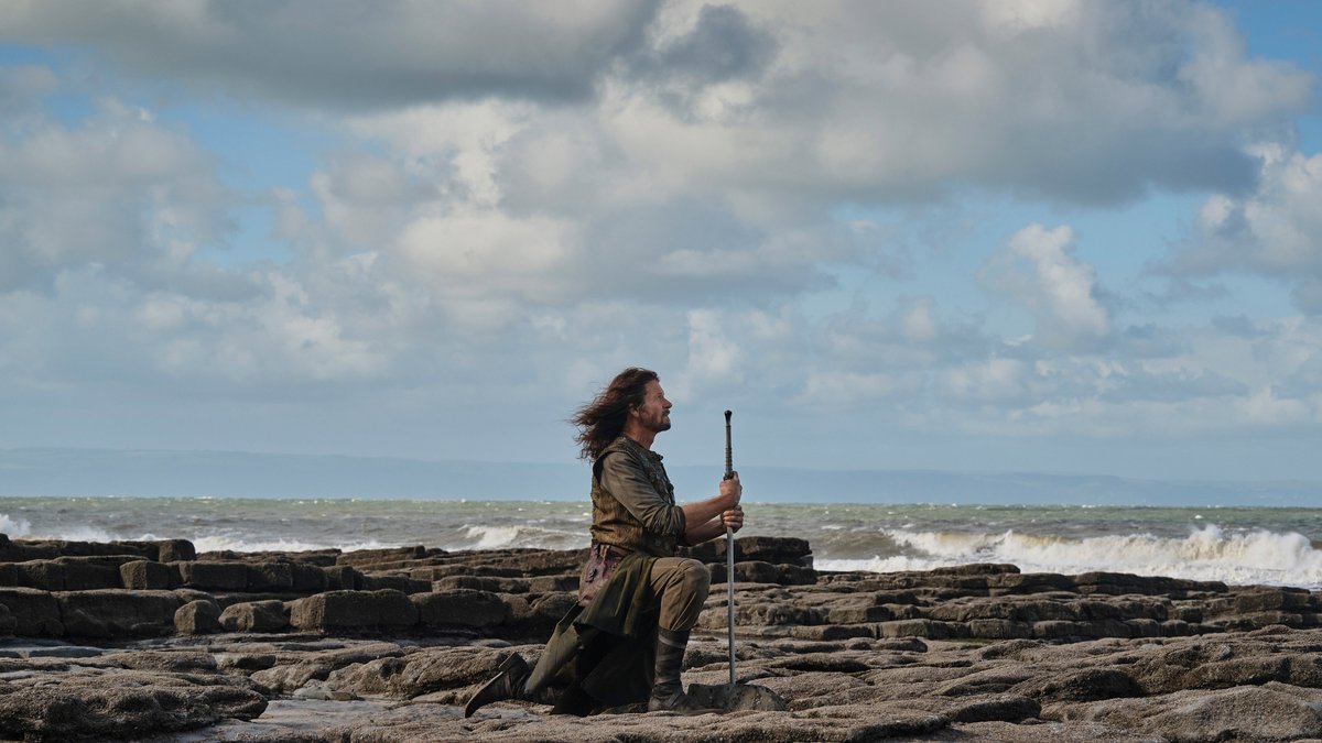 The Stranger sitting alone on a beach in The Lord of the Rings: The Rings of Power.