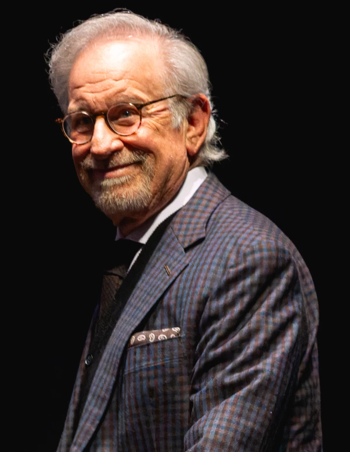 Steven Spielberg wearing glasses and a checked jacket, photographed in 2025.