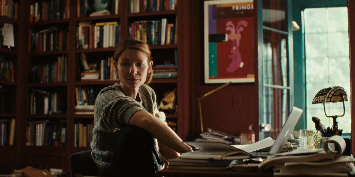 Claire Danes as Aggie Wiggs sits at a cluttered desk in a book-lined room in a Season 1 still from Netflix's The Beast in Me.