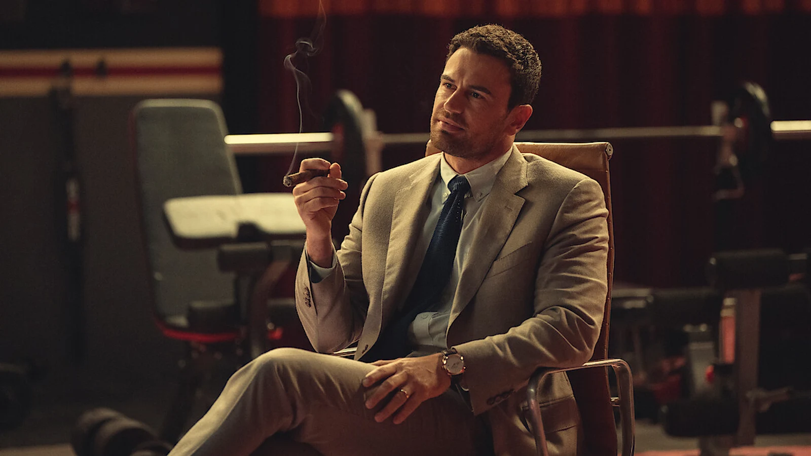 Theo James as Eddie Horniman sitting with a lit cigar in the closing scene of The Gentlemen Season 2 finale.