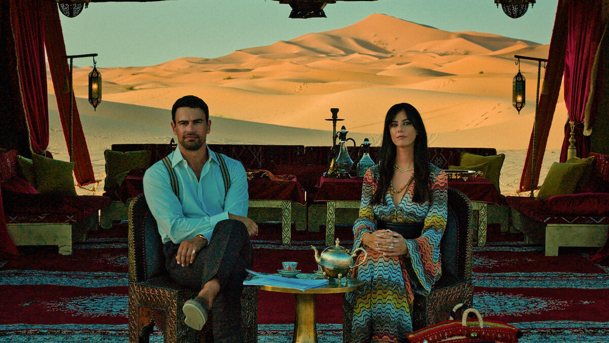 Theo James and Kaya Scodelario seated inside a tent overlooking desert dunes in Netflix’s Season 3 production photograph.