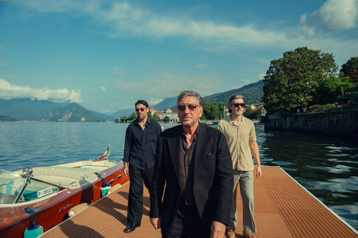 Sergio Castellitto as Marco Moretti walking on a lakeside dock in The Gentlemen Season 2.