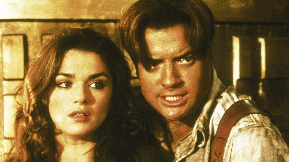 Rachel Weisz as Evelyn and Brendan Fraser as Rick O'Connell stand together in an archival Mummy film image.