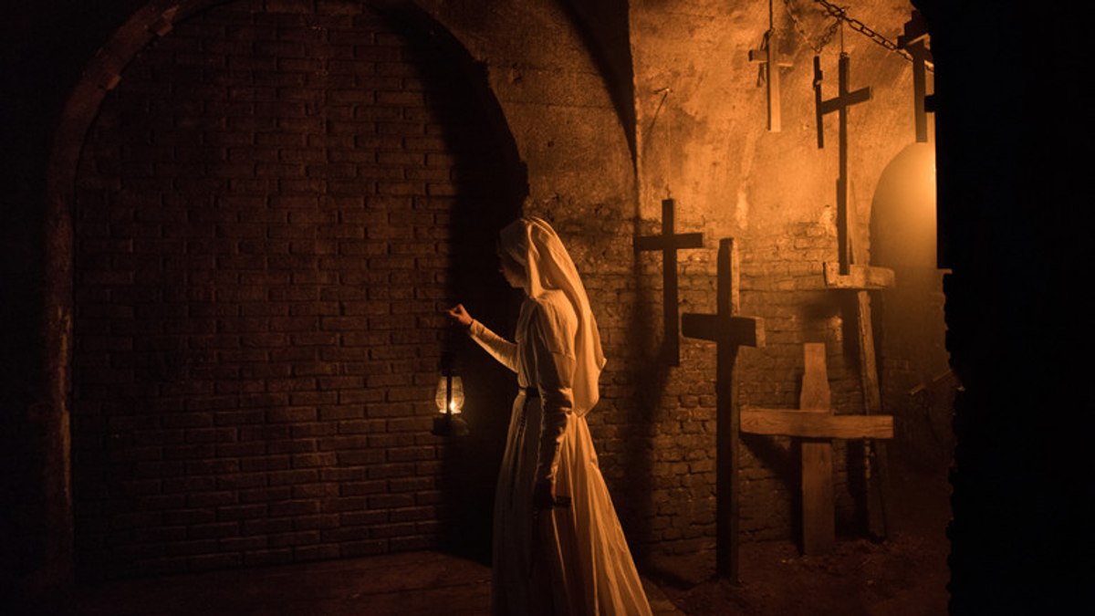 The candlelit crypt beneath Saint Cârța Abbey, lined with wooden crosses, in The Nun (2018).