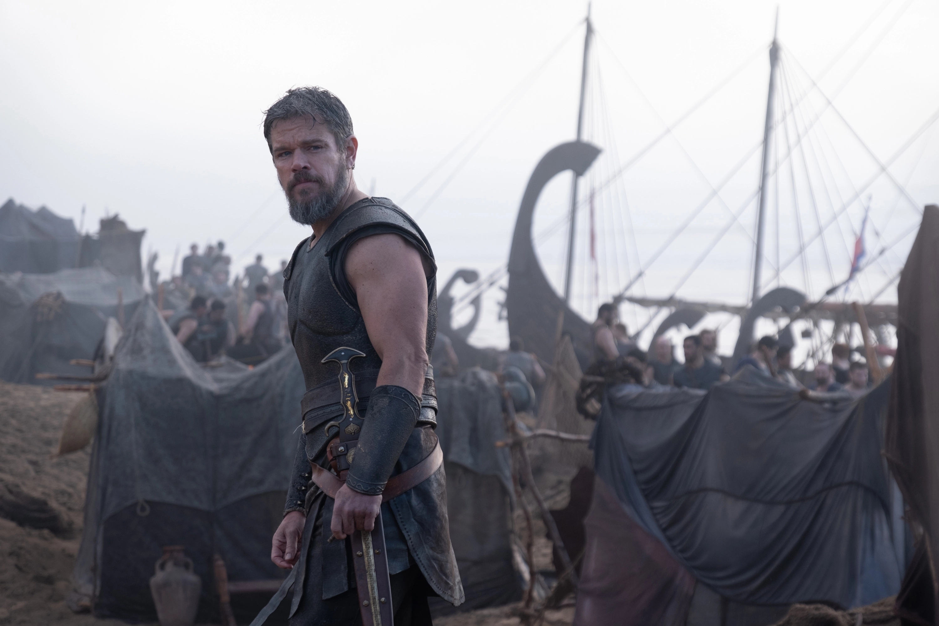 Matt Damon as Odysseus standing near Greek ships in Christopher Nolan's The Odyssey.
