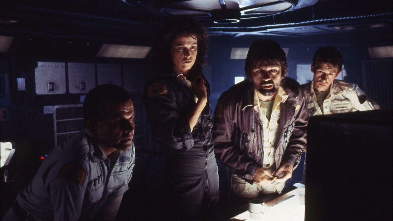 Tom Skerritt as Captain Dallas leaning over a computer with fellow Nostromo crew members in Alien (1979).