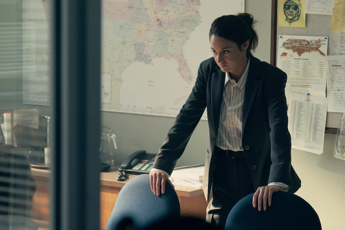 Shailene Woodley as the fictional FBI agent Joanne Miller leans over chairs in an investigation office in UNABOMBER.