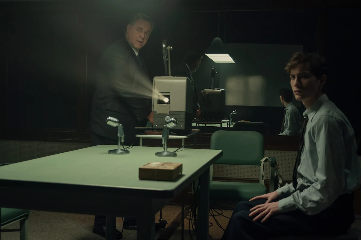Russell Crowe as Henry Murray stands beside a projector while Jacob Tremblay as Ted Kaczynski sits across the table in UNABOMBER.