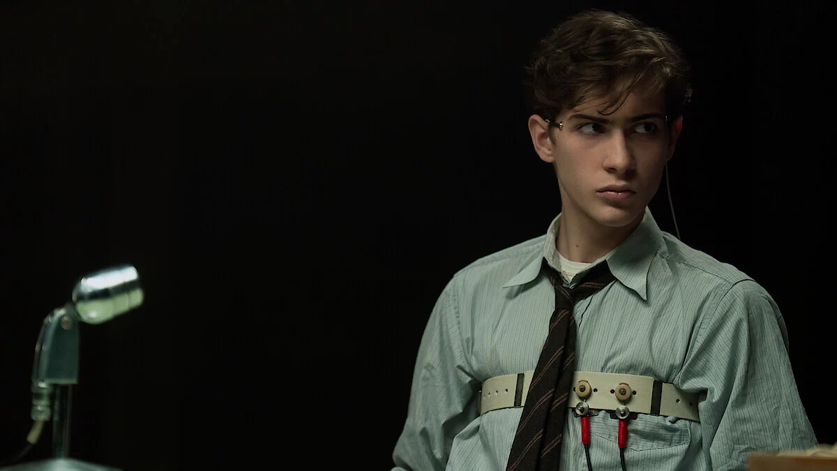 Jacob Tremblay as young Ted Kaczynski sits attached to a polygraph apparatus beside a microphone in Netflix’s UNABOMBER.